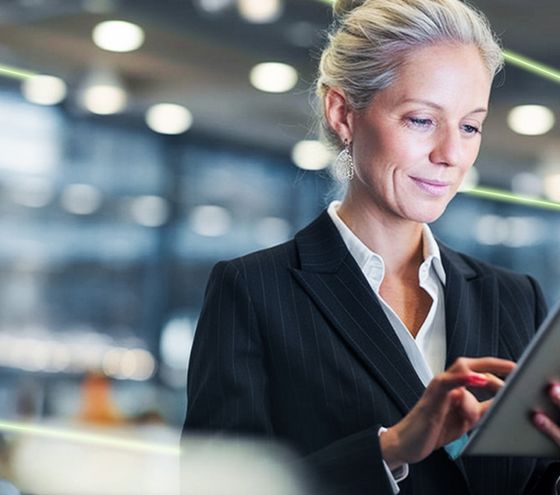Businesswoman working focused with a tablet in a modern office environment.