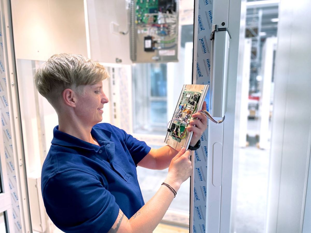 Eine KEBA-Mitarbeiterin Mitarbeiterin installiert und überprüft eine elektronische Steuerplatine bei einem KEMAS-Schleusensystem.