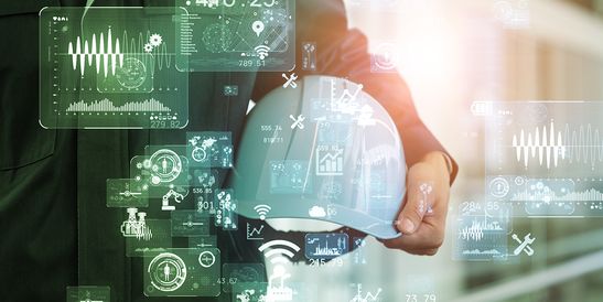 Person mit einem Schutzhelm, auf dem digitale Datengrafiken wie Diagramme und Technologiesymbole eingeblendet sind, was auf ein intelligentes Baukonzept hindeutet.