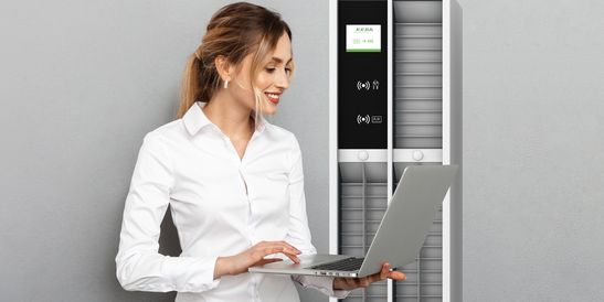 Woman with a laptop standing in front of a KeMas Terminal