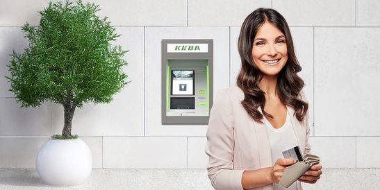 Smiling woman holding cards stands near a KEBA cash recycler, with a potted plant in the background.