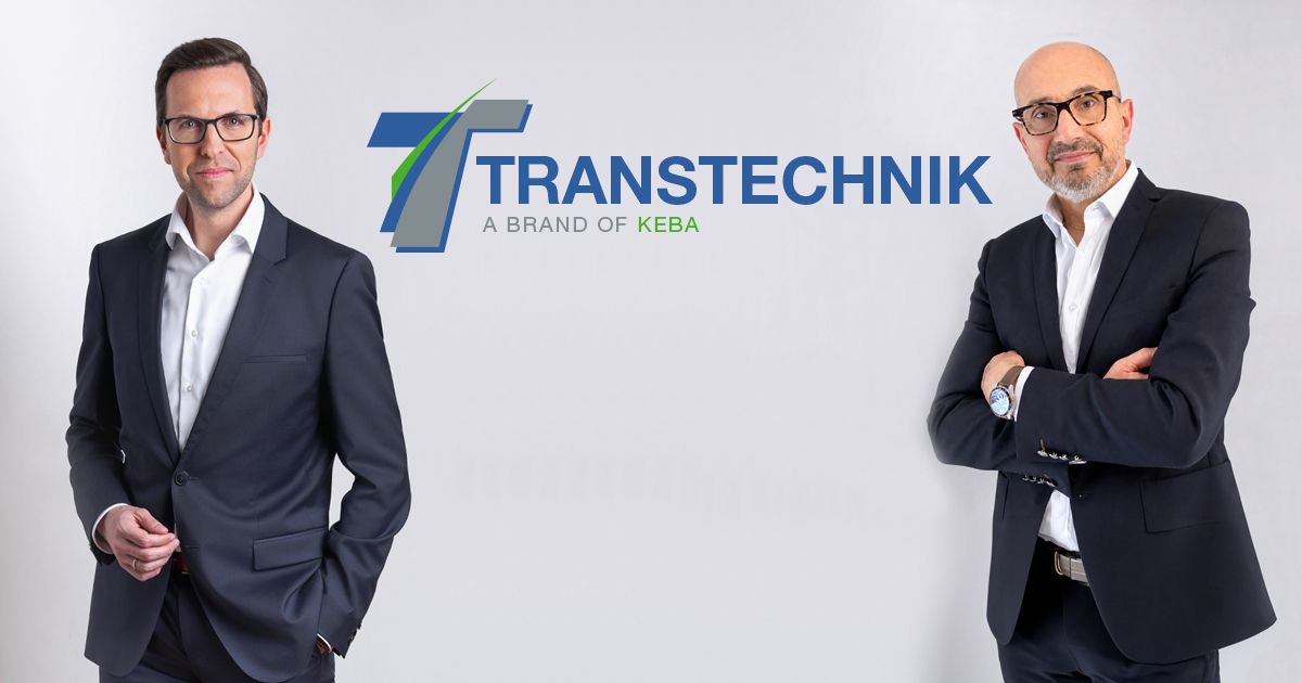 Christoph Knogler, CEO of the KEBA Group, and Bruno Coupechoux, Managing Director of Transtechnik, stand in business attire against a light background. The Transtechnik logo with the tagline “A Brand of KEBA” is displayed between them. Both face the camera, conveying a professional and collaborative impression.