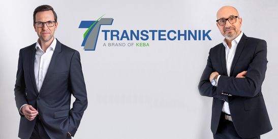 Christoph Knogler, CEO of the KEBA Group, and Bruno Coupechoux, Managing Director of Transtechnik, stand in business attire against a light background. The Transtechnik logo with the tagline “A Brand of KEBA” is displayed between them. Both face the camera, conveying a professional and collaborative impression.