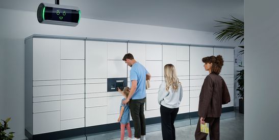 Moderne Bankfiliale mit Personen an Geldautomaten, KI-Assistent KeBob im Einsatz und Kunden beim Betreten durch Glastüren.