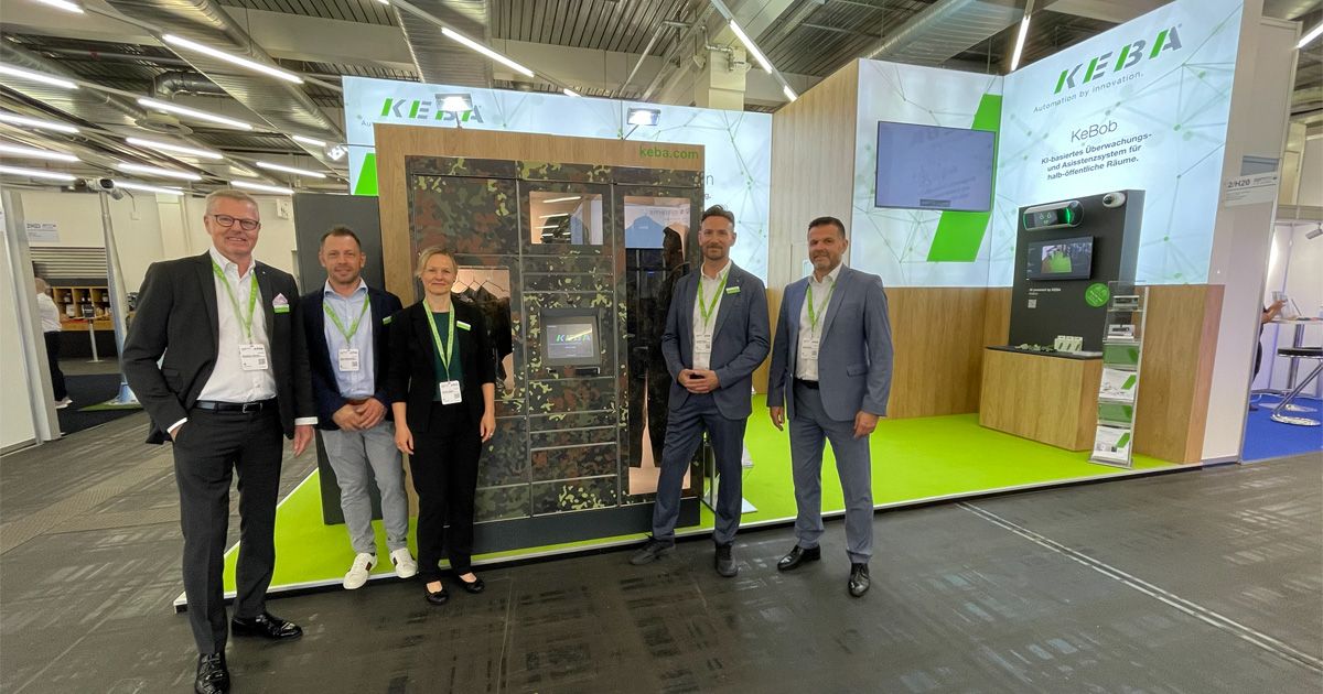 Fünf Personen stehen vor einem Messestand mit KEBA-Display und blicken lächelnd in die Kamera.