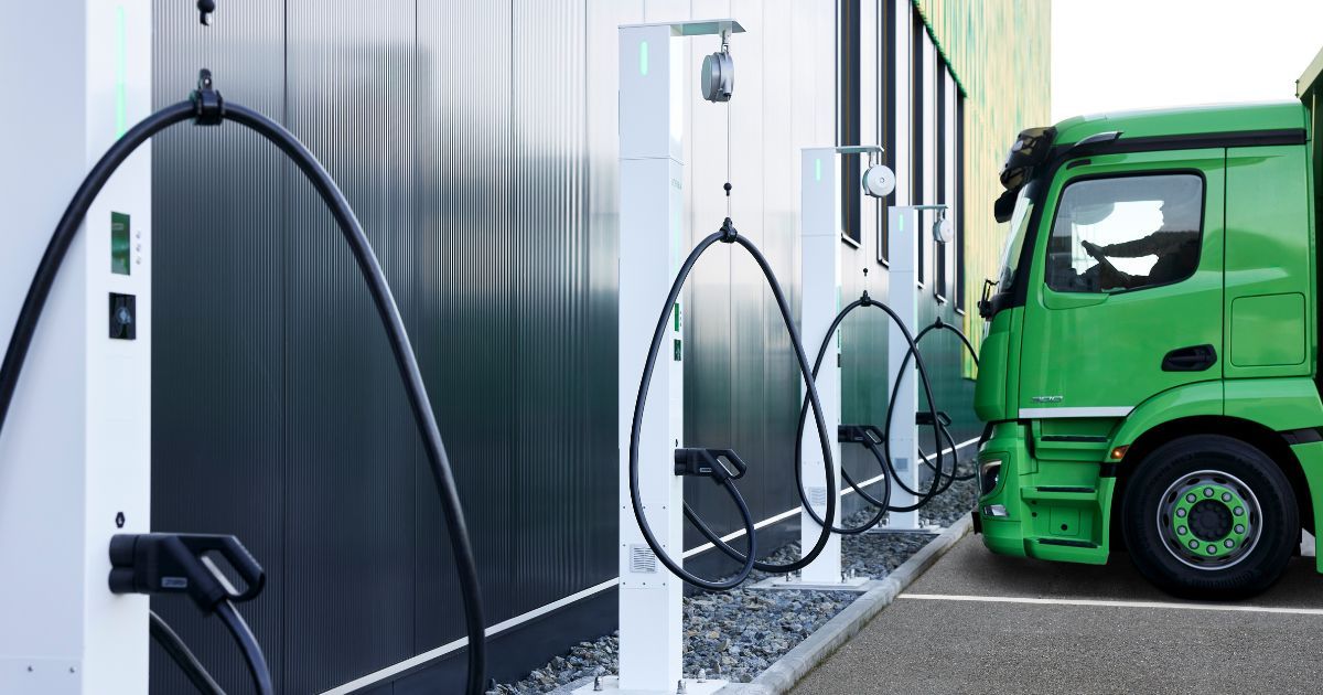 Multiple charging stations for electric trucks at a depot, with a green Freistädter truck connected to one of the units.