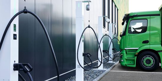 Multiple charging stations for electric trucks at a depot, with a green Freistädter truck connected to one of the units.