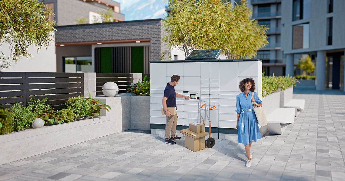 Outdoor parcel locker in a modern residential area with plants and contemporary buildings in the background.