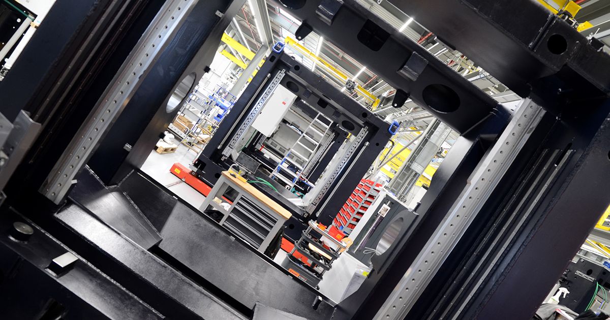 View through the frame of several machine structures being assembled in a production hall – symbolizing precision, engineering, and industrial manufacturing processes.