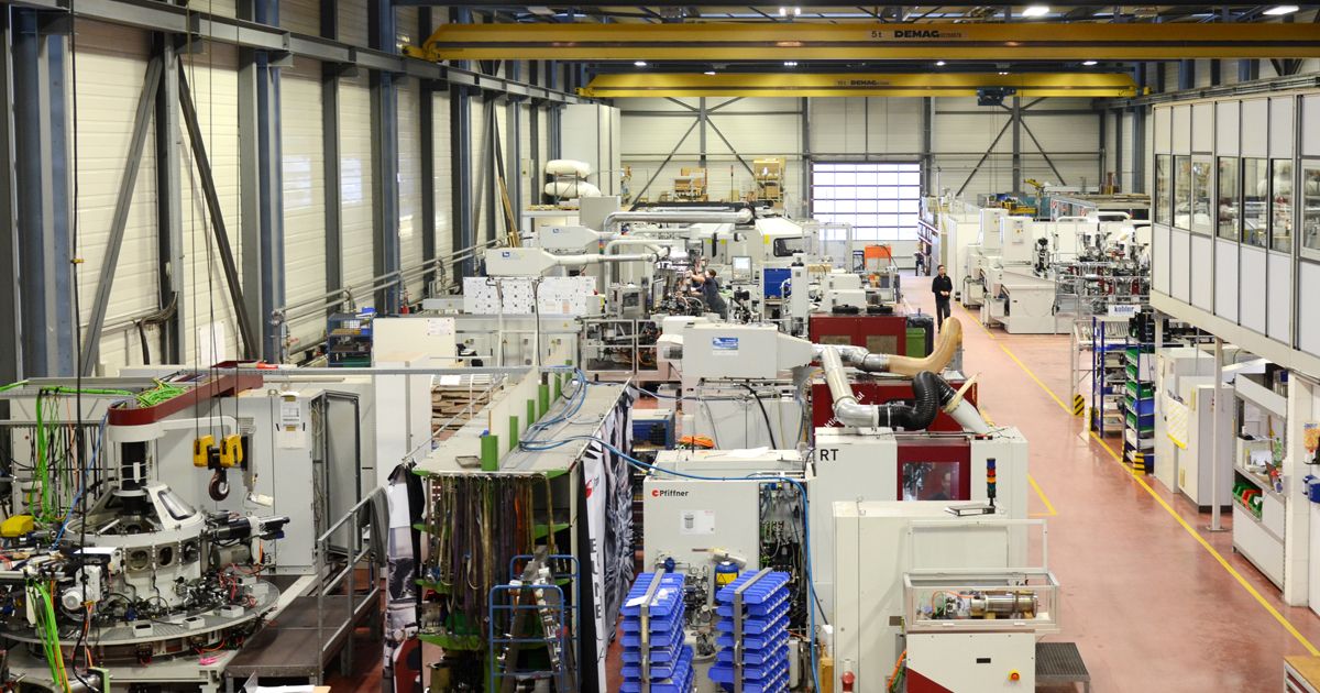 Overview of a modern production hall featuring numerous automated machines, manufacturing cells, and control systems. The image represents efficient, digitally connected industrial production and precise automation technology.