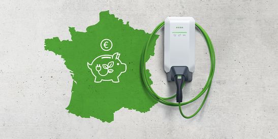 Un chargeur de véhicule électrique blanc avec un câble vert est placé sur une carte de France, présentant une tirelire avec un symbole de prise électrique et un signe euro.
