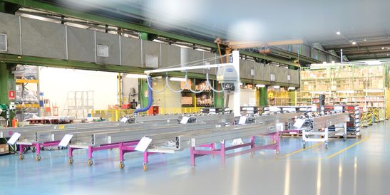 Production hall with automated conveyor systems and assembly lines in a bright industrial environment – symbolizing efficient manufacturing, modern plant control, and industrial automation.