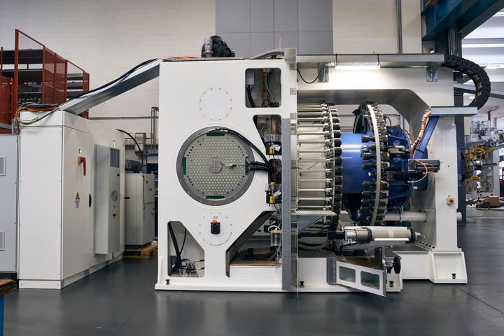 Large industrial production machine in a SPL manufacturing hall with a central drive and rotary system. The equipment is designed for industrial automation and precision control applications and is surrounded by several control cabinet and supply units. 