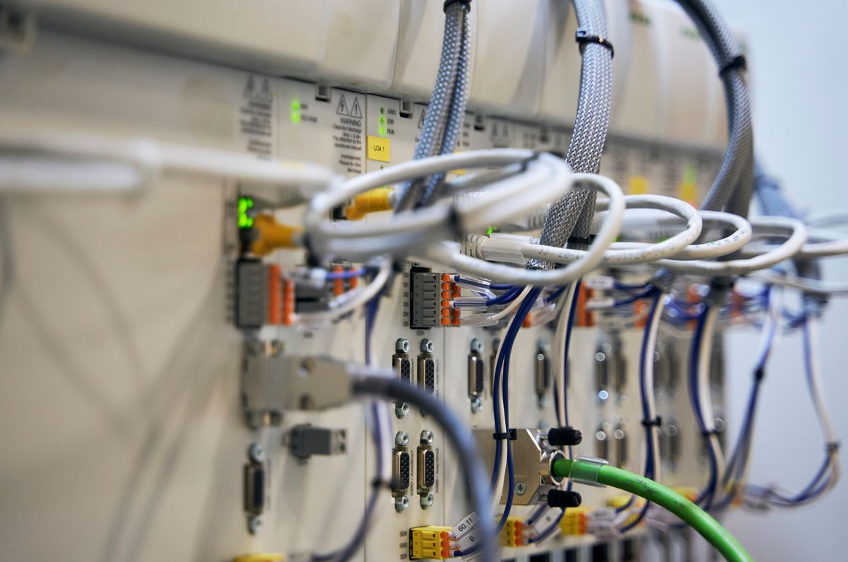 Close-up of control and servo drive components with connected communication and power cables inside an SPL production system. Each axis is driven by its own dedicated servo motor, while motion sequences are electronically coordinated by a central motion controller. 