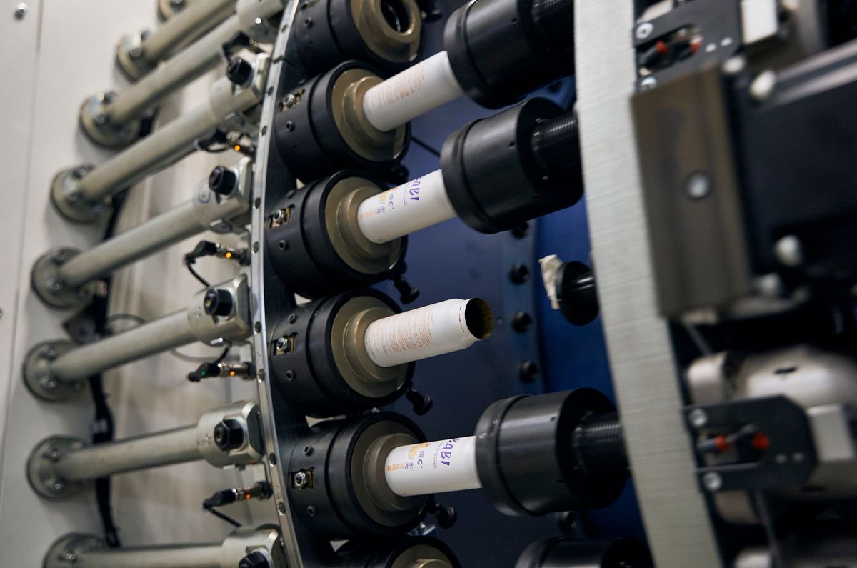 Close-up of an SPL production machine with multiple rotating spindles and wound material rolls during operation. The system handles large masses at high speed and precision for industrial automation applications.