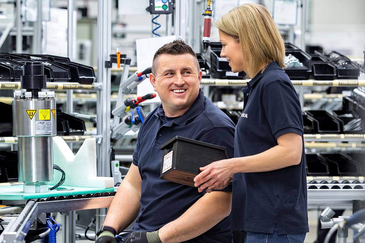 Zwei KEBA-Mitarbeiter:innen in der Produktion im engagierten Austausch – Teamarbeit und Freude am Arbeitsplatz.