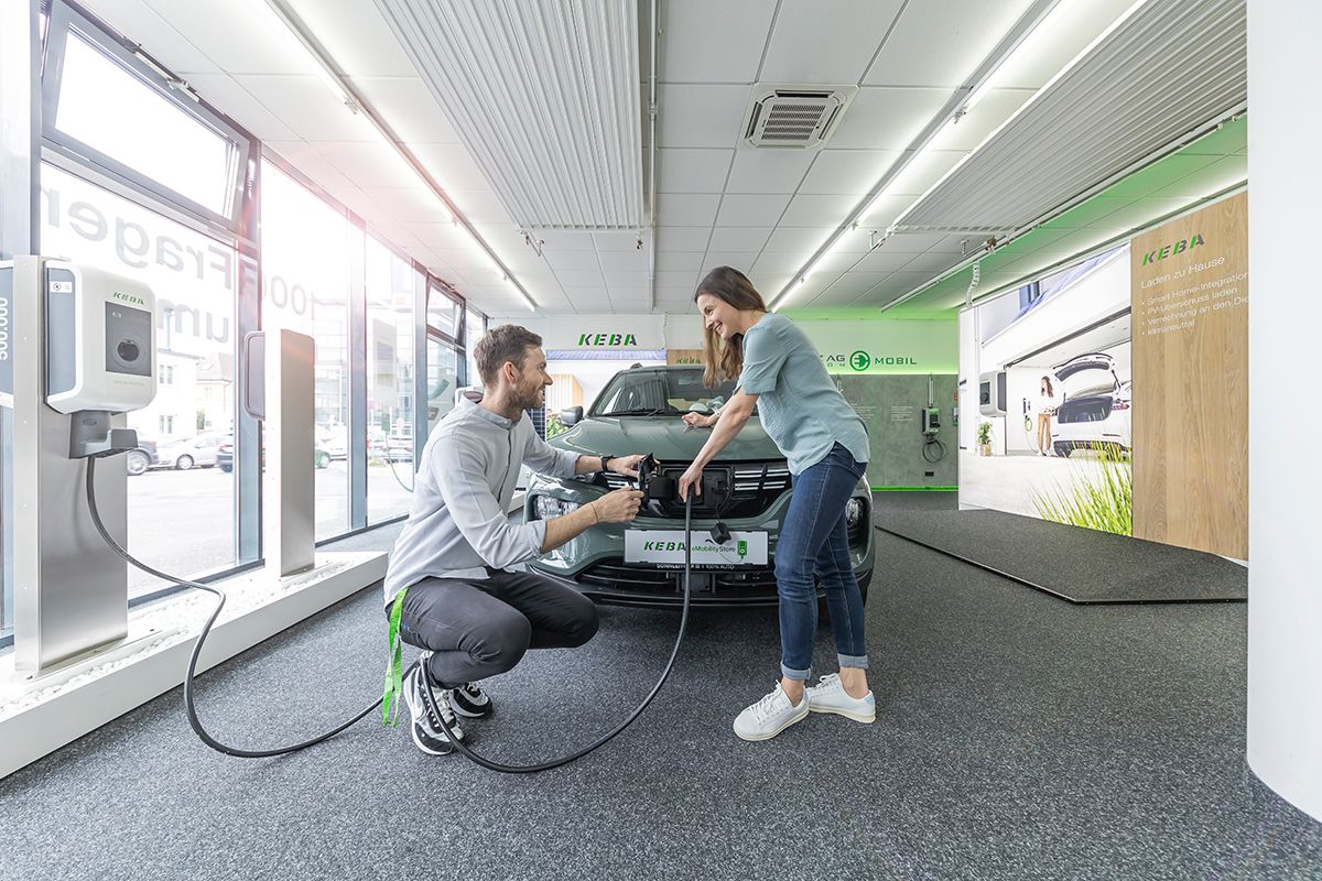 Employee shows a woman how to charge an electric car.