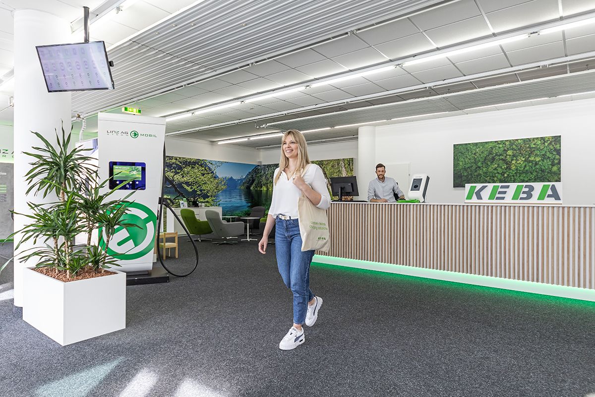 Woman enters the reception area of the KEBA Store with a welcome sign.