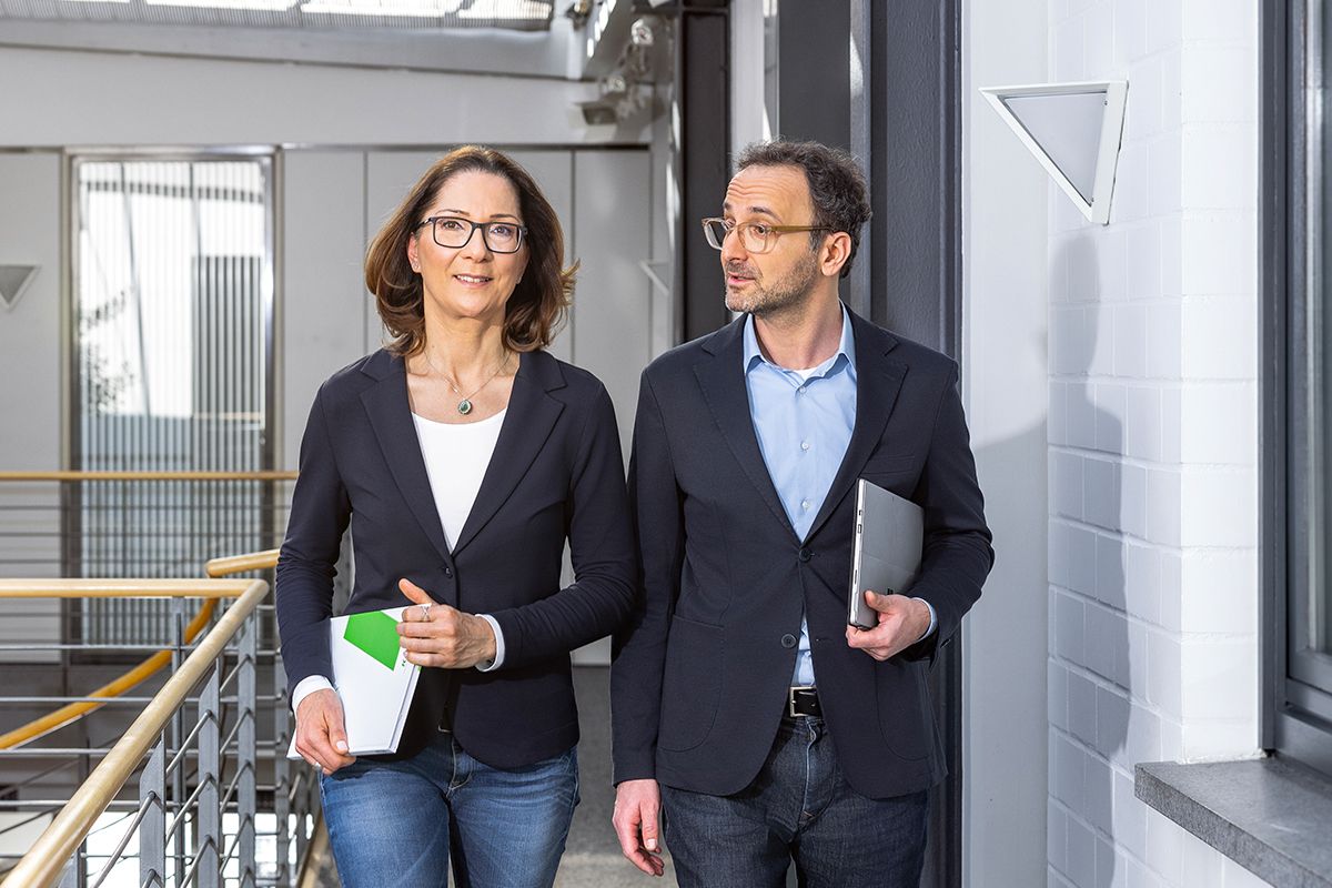 Zwei KEBA-Mitarbeitende im Gespräch auf dem Weg durch das moderne Bürogebäude – Teamwork und Austausch in einer inspirierenden Arbeitsumgebung.