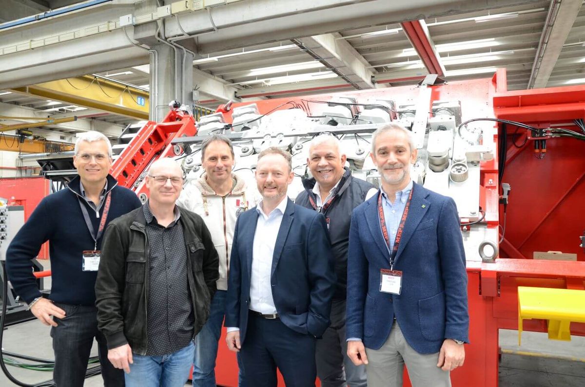 Sechs Personen aus dem MEP- und KEBA-Team stehen vor einer industriellen Rohrbearbeitungsmaschine im MEP-Werk. In der Mitte (mit weißem Hemd): Giles Haysom, Procurement Director MEP