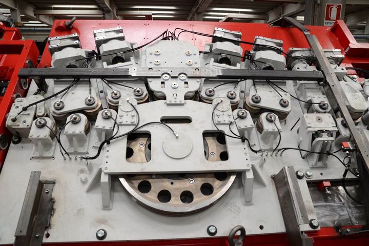 Frontalansicht der komplexen Mechanik einer industriellen Maschine mit synchronisierten Rollen- und Antriebseinheiten.