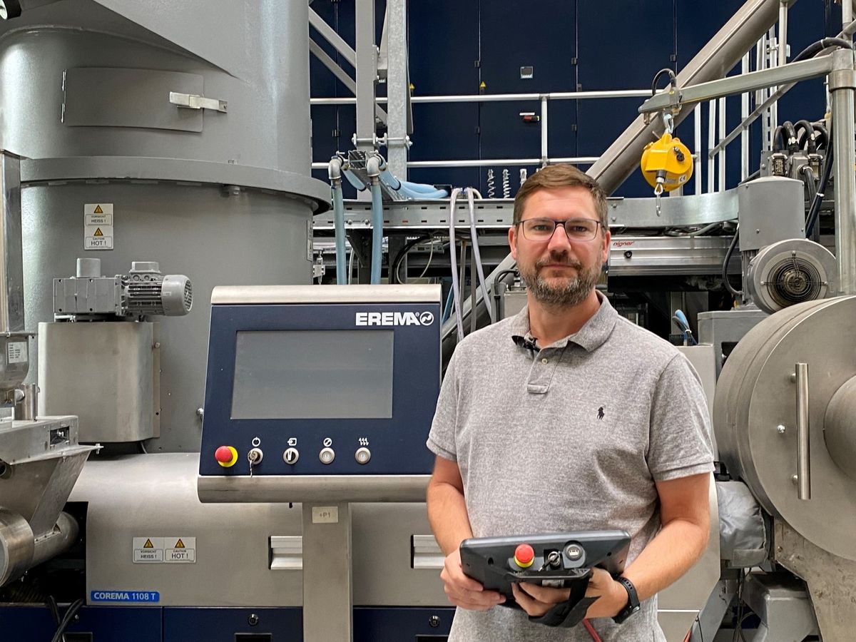 Ingenieur steht vor einer EREMA-Anlage mit großem Bedienpanel und hält ein mobiles Steuergerät – Beispiel für den Einsatz von KEBA-Automatisierungslösungen in der Kunststoffrecycling-Industrie.