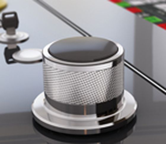 A metallic KeWheel rotary pushbutton on a machine control panel with buttons and controls in the background.