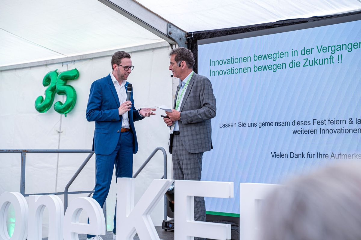 KEBA CEO Christoph Knogler and Volker Rattmann speak on a stage next to a large "35" sign. A screen displays German text about innovation.