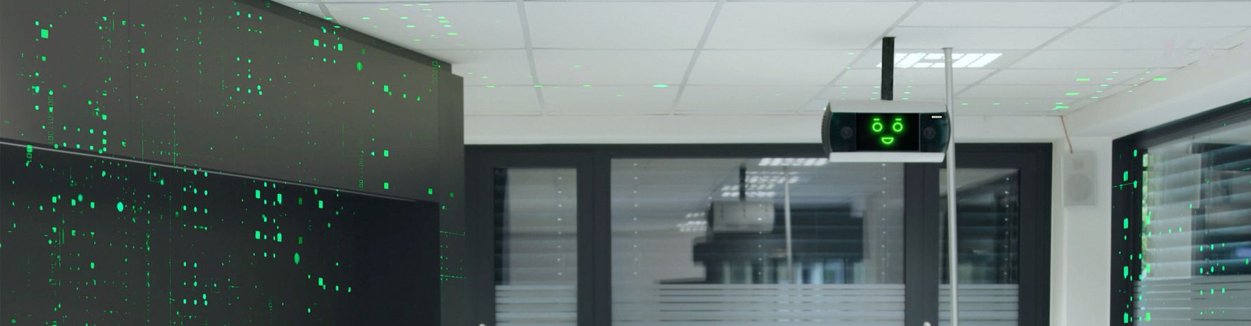 Moderne Büro-Lobby mit KeBob, der von der Decke hängt und ein fröhliches Gesicht zeigt. Die Wände sind mit grünen digitalen Mustern gestaltet.