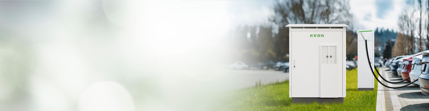 KeContact DCU10 Power Unit, une unité de charge modulaire pour parcs de recharge. À gauche, le texte « KeContact DCU10 Power Unit » avec le sous-titre « Puissance modulaire pour le parc de recharge » sur fond blanc. À droite, un grand chargeur blanc avec le logo KEBA sur une pelouse. En arrière-plan, des voitures stationnées et des arbres.