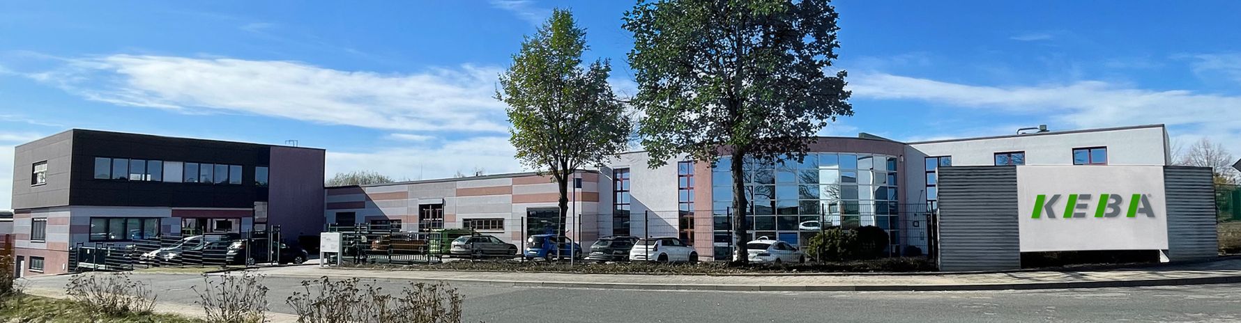 Modernes KEBA-Gebäude mit Logo vor blauem Himmel.