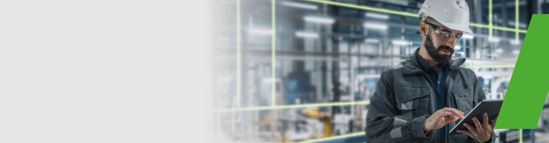 Engineer wearing a safety helmet working with a tablet in a modern industrial environment.