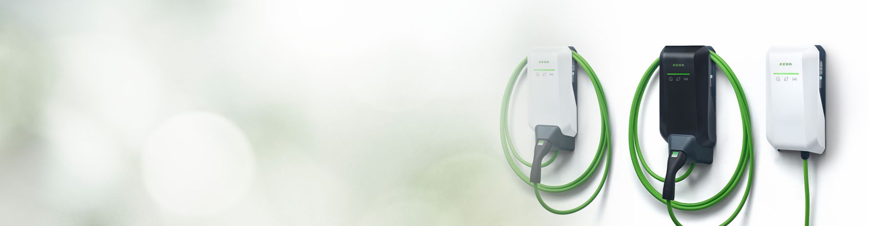 Immagine header con tre wallbox KeContact P40 Pro: una nera al centro, due bianche a sinistra e a destra. Il cavo di ricarica verde è visibile, sfondo bianco con sfumatura verde.