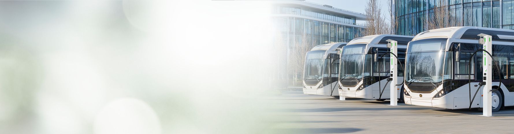 Several buses are charging at KeContact DCL10 pillar charging stations in front of a modern building.
