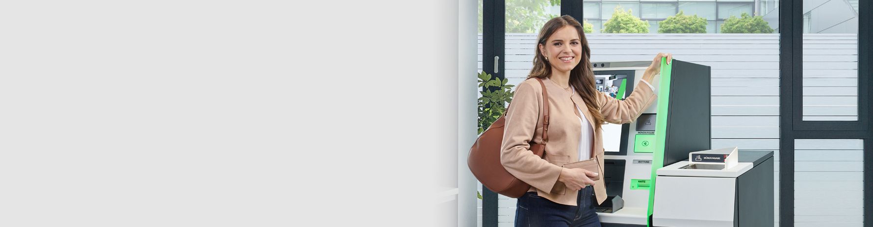 Eine lächelnde Frau steht neben einem Cash-Recycler in einem hellen Raum.