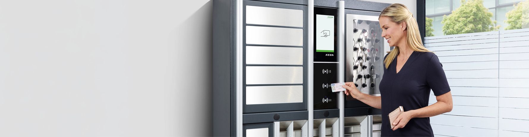 Una donna utilizza una tessera per aprire uno scomparto in un terminale di consegna sicuro, dotato di grandi scomparti metallici e di un display digitale.