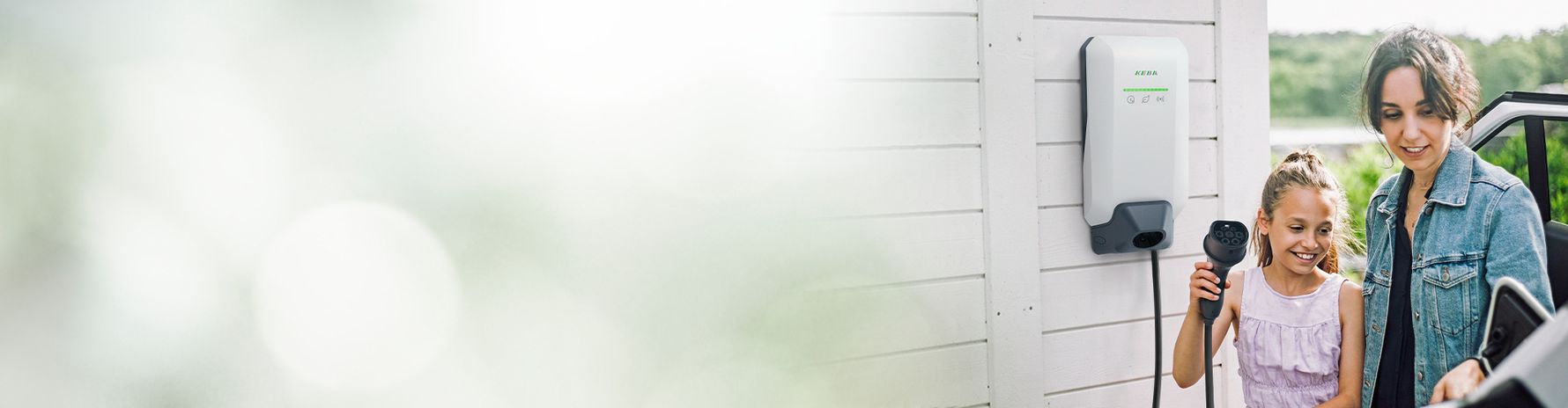 Une femme recharge sa voiture électrique avec la KeContact P40, accompagnée de son enfant.