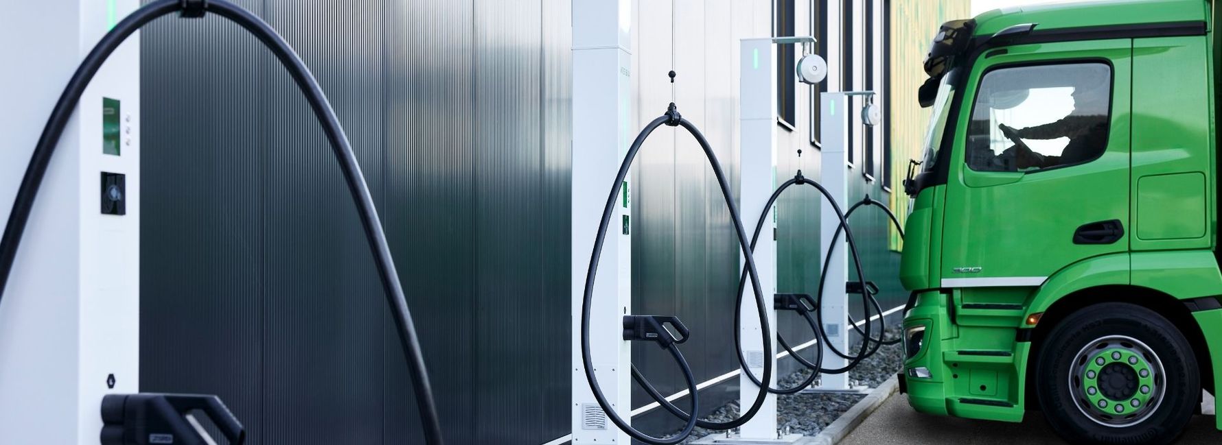 Grüner Elektro-Lkw an einer Reihe von DC-Ladestationen für Transport und Logistik.