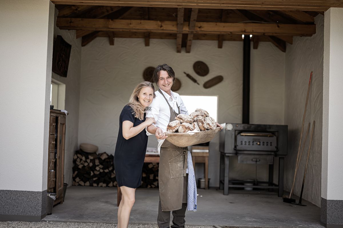 Eva-Maria Pürmayer and Thomas Hofer standing together in a bakery with fresh bread.