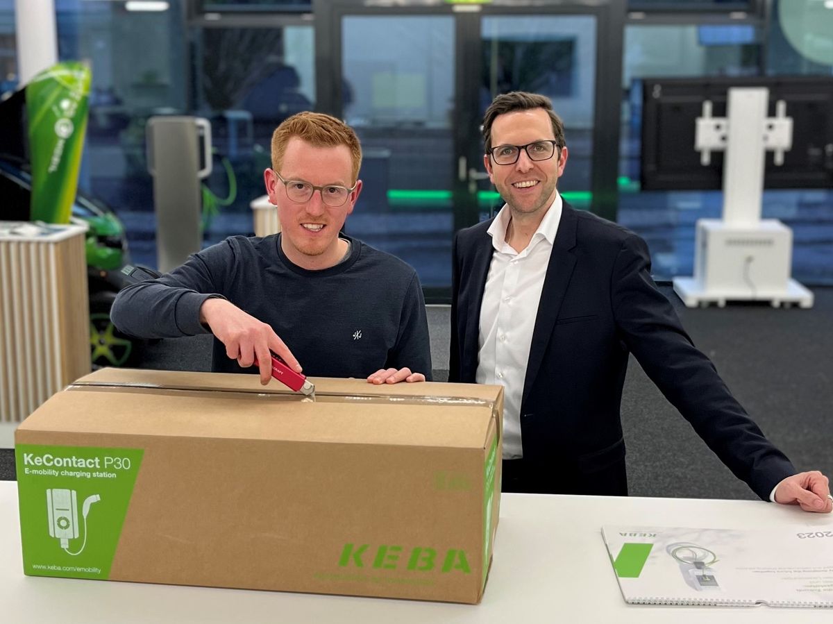 Two men unbox a large package containing a KEBA KeContact P30 wallbox.