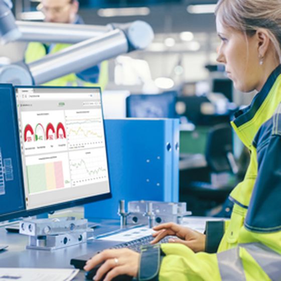 A person monitoring and analyzing production and quality data on a screen in an industrial manufacturing environment.