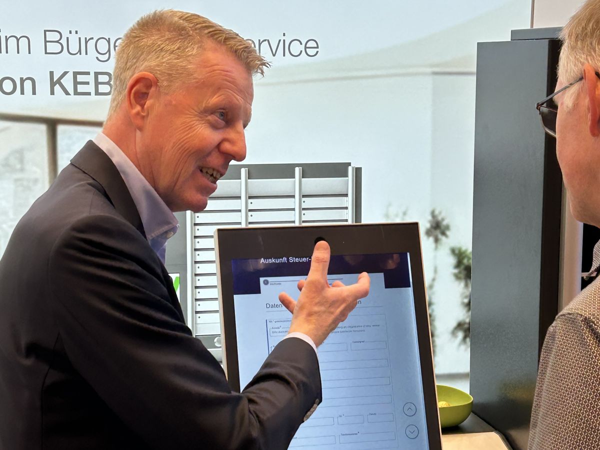 Zwei Männer stehen an einem Ausstellungsgerät auf einer Messe und unterhalten sich darüber