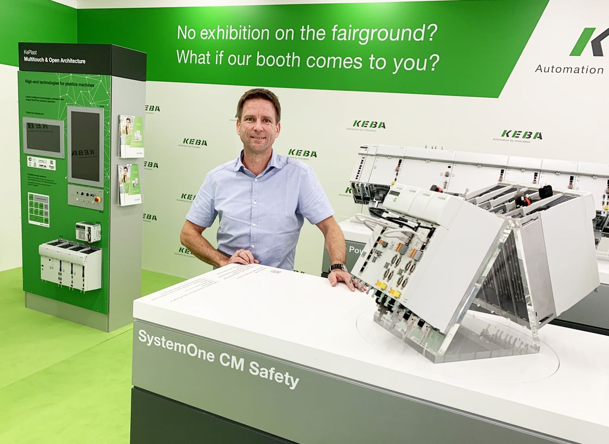 KEBA employee stands behind an exhibit at a booth..