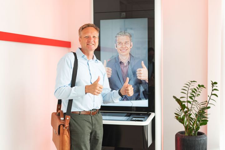 Kunde vor einem InfoGate-Counter, der mit einem Bankberater verbunden ist