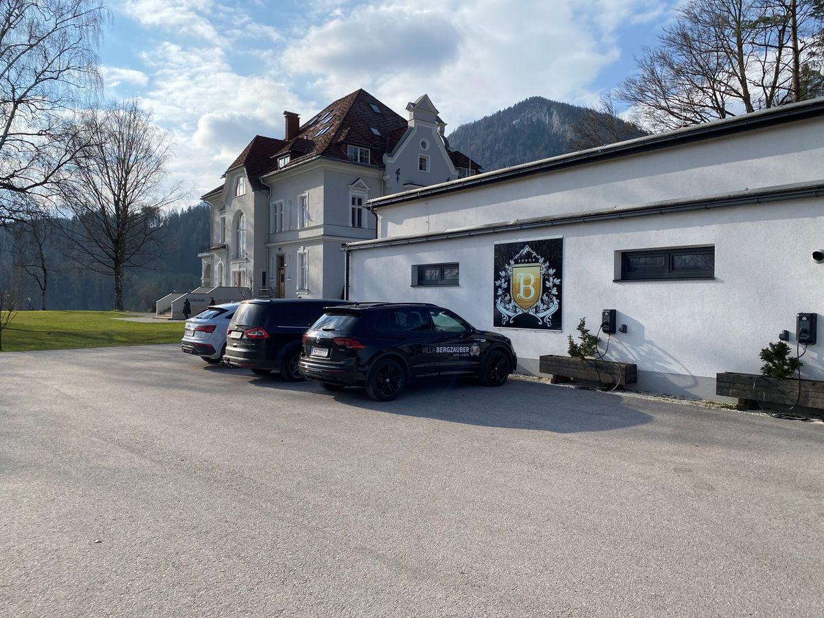 Drei Fahrzeuge parken vor dem Nebengebäude der Villa Bergzauber, mit sichtbarer Ladeinfrastruktur.