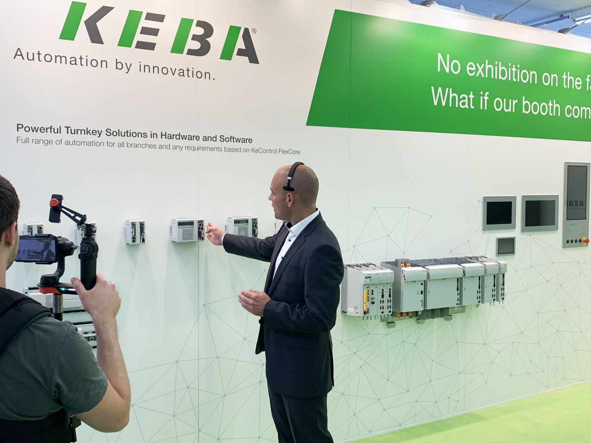 KEBA employee explains exhibits hanging on a wall.