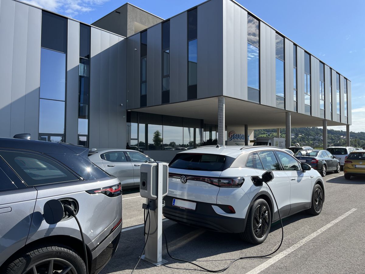 Elektrofahrzeuge sind an mehreren KEBA-Ladestationen auf einem Firmenparkplatz angeschlossen.