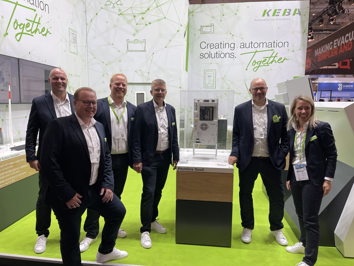 Visitors watch a pick-and-place robotic cell using the Kemro X platform at the KEBA exhibition booth, controlled via an open automation environment with visualization on a large screen.