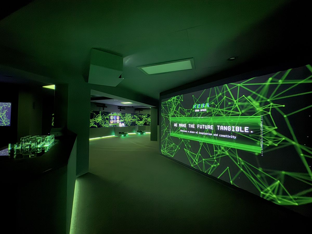 The KEBA InnoSpace presents itself as a visionary experience space with immersive projections, glowing network graphics, and the guiding principle "We make the future tangible" – a place of innovation, inspiration, and digital interaction.