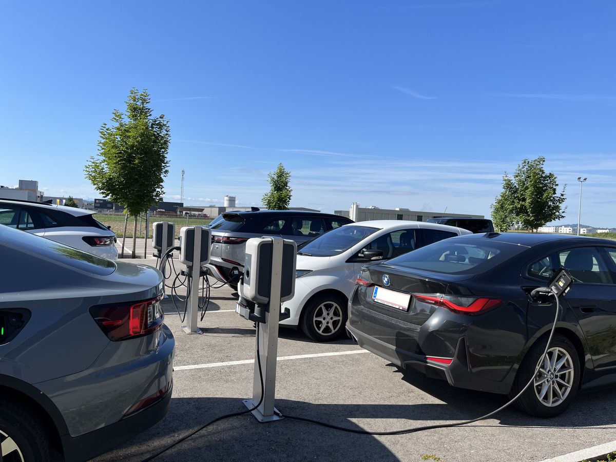 Mehrere Elektrofahrzeuge laden gleichzeitig an KEBA-Ladestationen auf einem sonnigen Parkplatz.